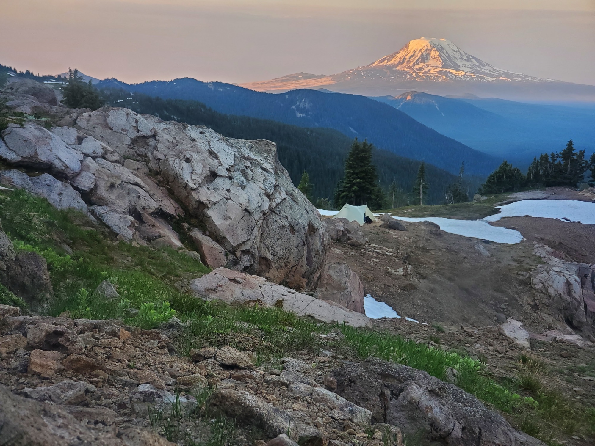 Snow-covered Mount Rainier rising beyond alpine meadows and exposed rock along the Pacific Crest Trail